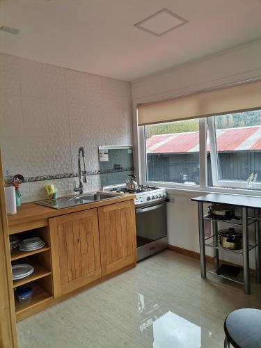 a kitchen with a sink and a stove and a window at Departamento Rossbach in Puerto Puyuhuapi