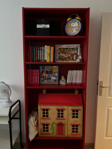ein rotes Bücherregal mit einem Spielzeughaus und einer Uhr in der Unterkunft Tenerife apartamento Sun Beach & Relax in Puertito de Güímar