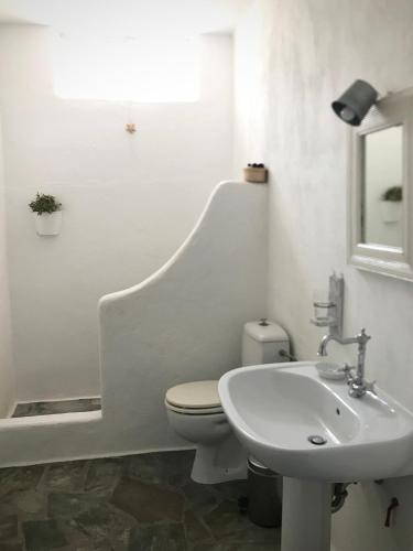a white bathroom with a toilet and a sink at Idyllic Sea Views for 2 in Aspro Chorio Paros