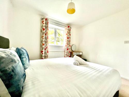 a bedroom with a large white bed and a window at Comfortable 3 bedroomed house in Bicester in Bicester