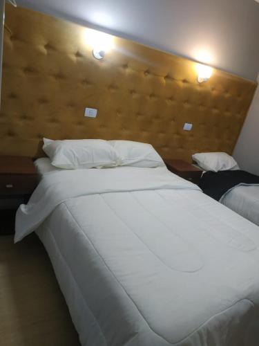 a bedroom with a large white bed with a wooden headboard at Hotel Ruta 66 Oficial in Paso de los Libres