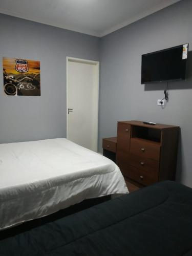 a bedroom with a bed and a dresser with a flat screen tv at Hotel Ruta 66 Oficial in Paso de los Libres