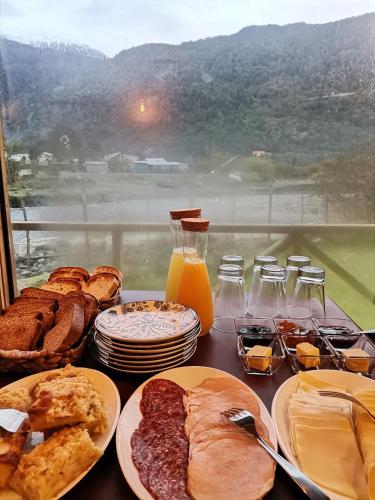 a table topped with plates of breakfast foods and a window at Departamento Rossbach in Puerto Puyuhuapi