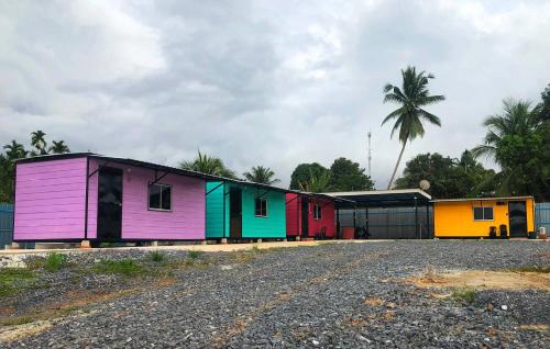 a row of colorful buildings with a palm tree in the background at Padang Besar Rainbow Cabin Homestay in Padang Besar