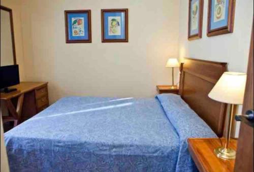Cette chambre comprend un lit bleu et un bureau. dans l'établissement Sierra Nevada Plaza Andalucia localización fantástica, à Sierra Nevada