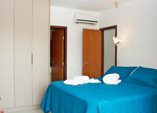 a bedroom with a blue bed with two towels at House Aconchegante Ponta Negra in Natal