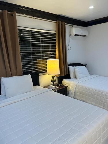 a bedroom with two beds and a lamp and a window at Colony Club Inn & Suites in Nassau