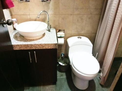 y baño con aseo blanco y lavamanos. en Confortable, en Guayaquil