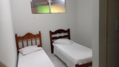 2 camas en una habitación con espejo en la pared en Pousada Nova en Montes Claros
