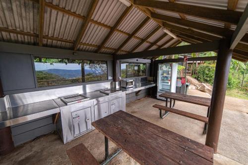 a kitchen with a bench and a table and windows at Binna Burra Rainforest Campsite in Beechmont
