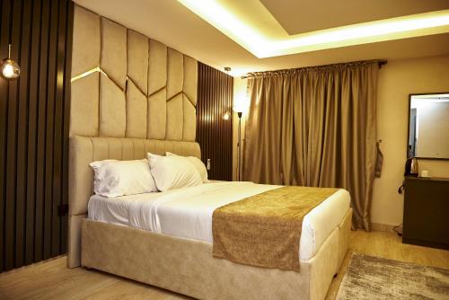 um quarto com uma cama grande e uma televisão em Mayfair Hotel Wuse2 Abuja em Abuja