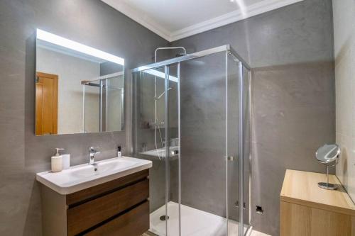 ein Bad mit einer Dusche, einem Waschbecken und einem Spiegel in der Unterkunft Amazing Apartment With Pool View in Vilamoura