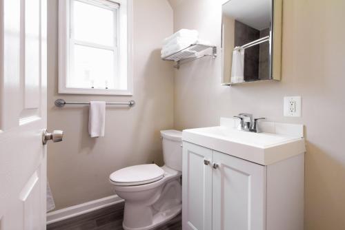 a bathroom with a toilet and a sink and a window at The Gray Corner House by Gallaudet 3 BR 2 BA in Washington