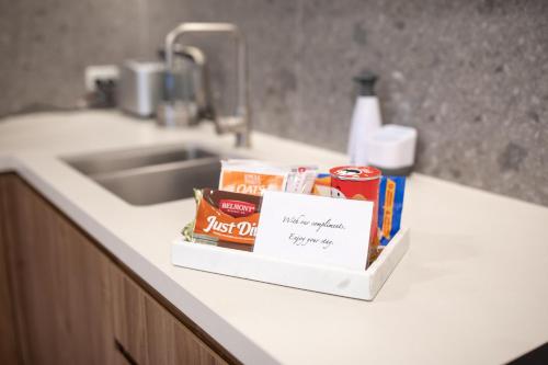 a kitchen counter with a sink with a box of food at The Hamptons - Lux 2 Bed 2 Bath, Pool - Central Location in Canberra