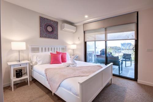 a bedroom with a white bed with red pillows at The Hamptons - Lux 2 Bed 2 Bath, Pool - Central Location in Canberra