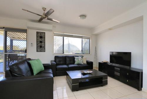 a living room with a black couch and a flat screen tv at Sandcastles 6 in Bargara