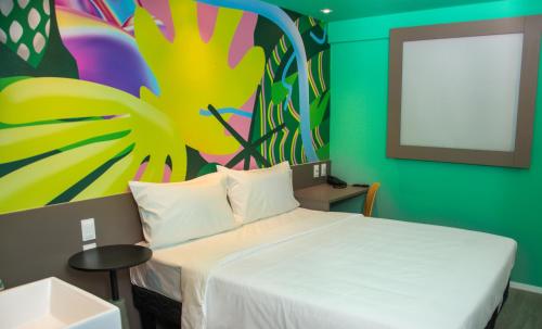 - une chambre avec un lit orné d'une peinture murale dans l'établissement Ibis Styles Garanhuns, à Garanhuns