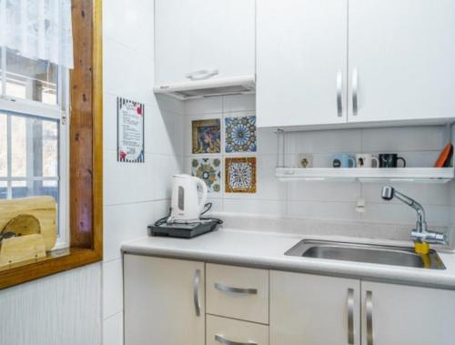 a kitchen with white cabinets and a sink and a window at Gilson Story Pension in Pyeongchang 
