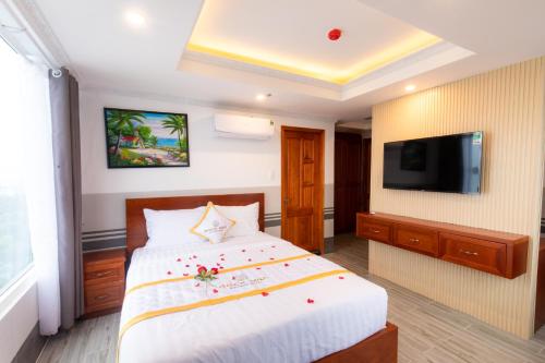a hotel room with a bed and a flat screen tv at Rockmila Hotel in Phu Quoc