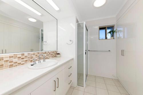 ein weißes Bad mit einer Dusche und einem Waschbecken in der Unterkunft Pacific Links 1b in Bargara