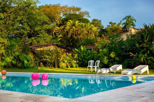 a swimming pool with chairs and a house at Pousada Chácara Maria da Graça in Tremembé