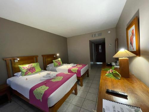 a hotel room with two beds and a table at Tiki Hôtel - Hôtel d'application du Lycée de Tahiti in Punaauia