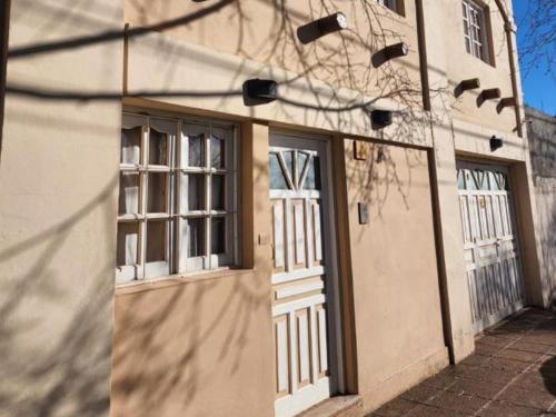 un edificio con puertas blancas y ventanas. en Malargue house II. en Malargüe