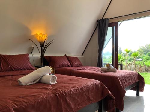 a bedroom with two beds and a large window at Batur Homestay and Lodge in Bangli