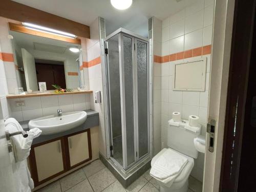 a bathroom with a shower and a sink and a toilet at Tiki Hôtel - Hôtel d'application du Lycée de Tahiti in Punaauia
