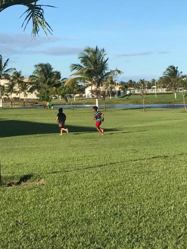 two people playing with a frisbee in a field at Villa das aguas -Praia do saco -Próximo as lagoas dos Tambaquis e Mangue Seco -térreo in Estância