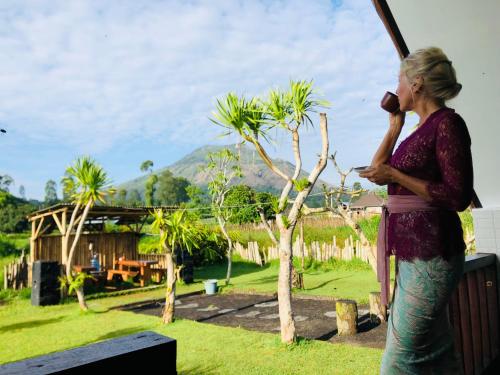a woman talking on a cell phone in a garden at Batur Homestay and Lodge in Bangli
