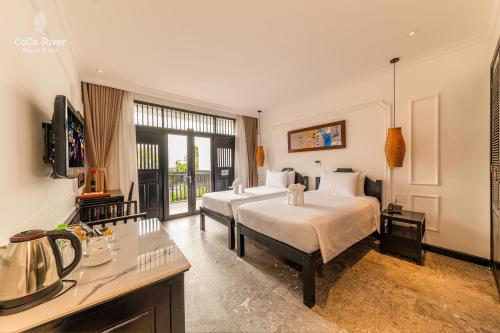 1 dormitorio con 2 camas y cocina con fregadero en Hoi An Coco River Resort & Spa, en Hoi An