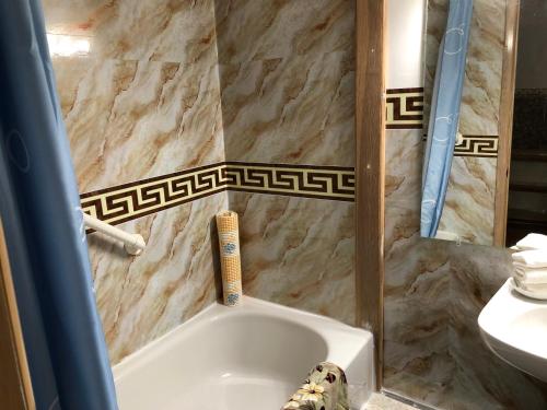 a bathroom with a bath tub with a tile wall at Heritage Place Hotel in Gravelbourg