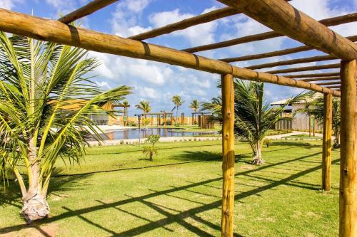 eine hölzerne Pergola mit Palmen und einem Pool in der Unterkunft Aloha Gostoso in São Miguel do Gostoso
