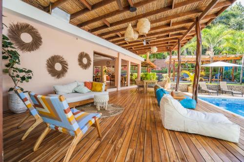 una sala de estar de planta abierta con piscina y suelo de madera. en Hotel Arco Iris en Tamarindo