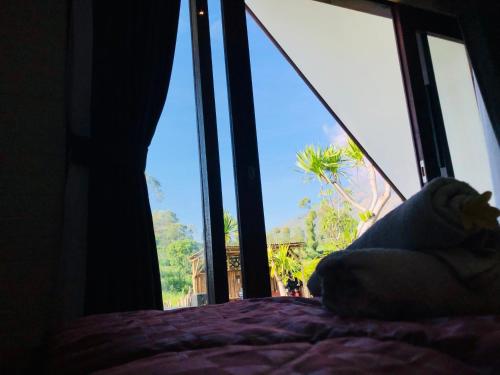 a bed in a room with a large window at Batur Homestay and Lodge in Bangli