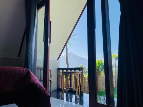 a bedroom with a window with a view of a balcony at Batur Homestay and Lodge in Bangli