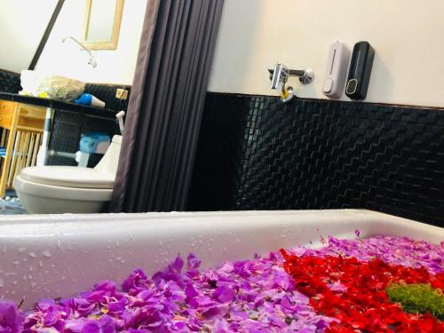 a bath tub filled with purple and red flowers at Batur Homestay and Lodge in Bangli