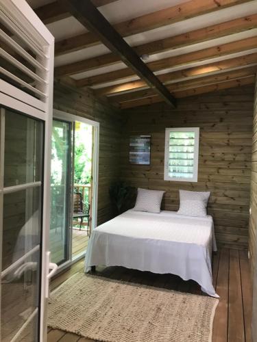 ein Schlafzimmer mit einem Bett in einem Holzhaus in der Unterkunft Chalet Colibri , Les ANSES d'ARLET 200 m plage in Les Anses-dʼArlets