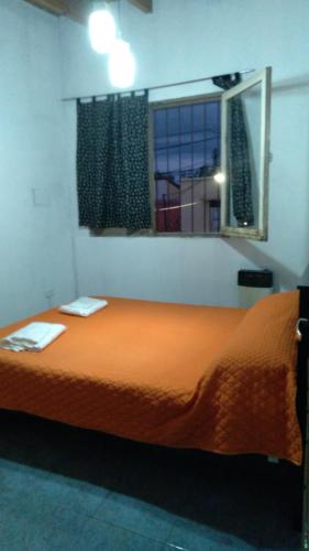 Cama naranja en habitación con ventana en Casa Villana en Mendoza