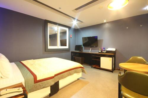 um quarto com uma cama, uma secretária e uma televisão em v motel em Busan