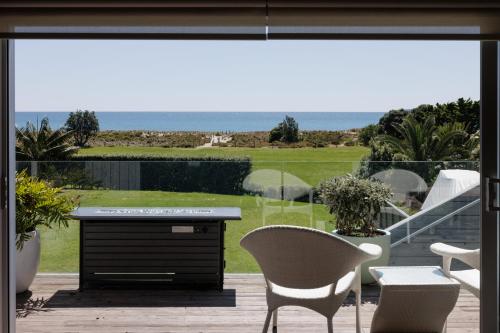 un patio con mesa y sillas y vistas al océano en Luxury Ocean Villa in Papamoa en Papamoa