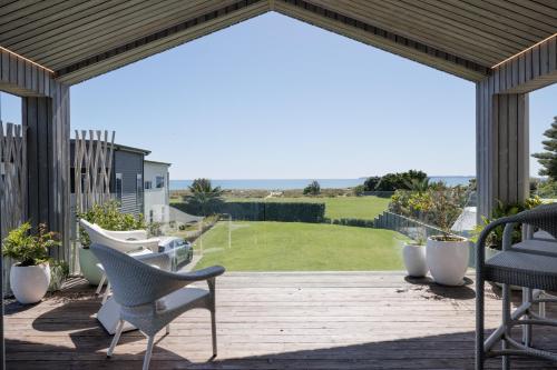 una terraza con sillas y vistas al océano. en Luxury Ocean Villa in Papamoa en Papamoa