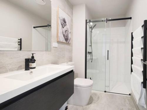 y baño con aseo, lavabo y ducha. en Brand new stylish 2BR apartment- free parking, en Auckland