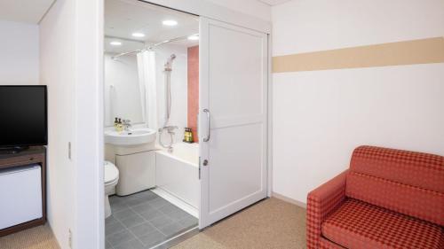 uma casa de banho com uma cadeira vermelha e um WC. em Art Hotel Niigata Station em Niigata