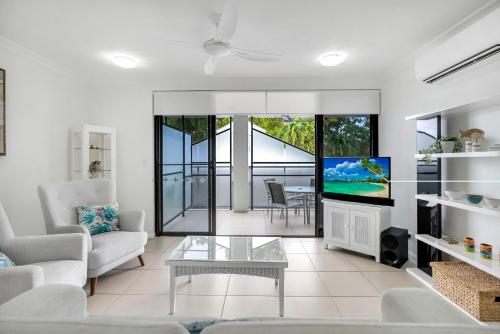 a living room with a couch and a tv at Elysium Apartments in Palm Cove