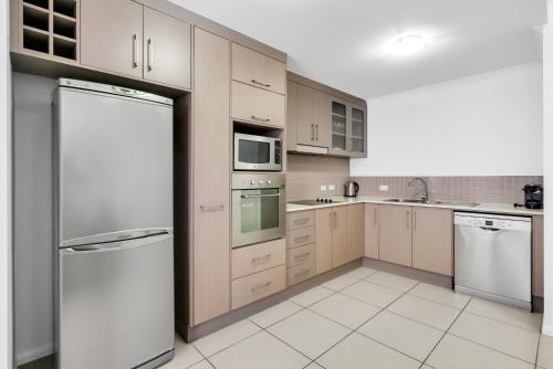 a kitchen with stainless steel appliances and white cabinets at Elysium Apartments in Palm Cove