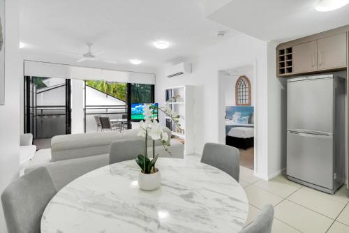 a kitchen and living room with a white table and chairs at Elysium Apartments in Palm Cove