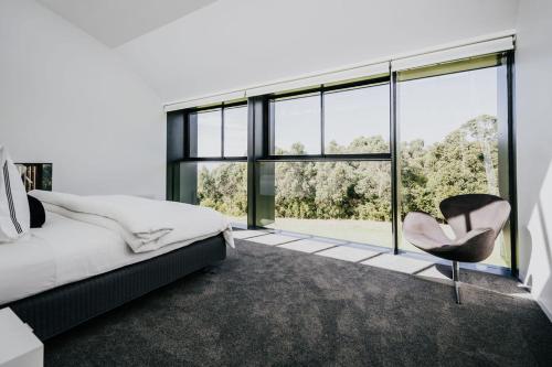 a bedroom with a chair and a large window at Alkina Lodge - Great Ocean Road in Wattle Hill