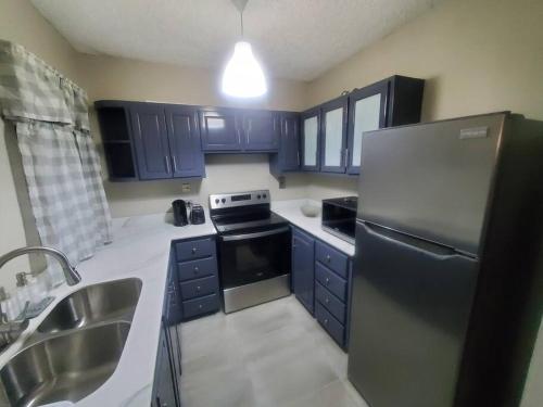 Una cocina con gabinetes azules y un refrigerador de acero inoxidable. en Modern Apartment at the Worthington, en Kingston